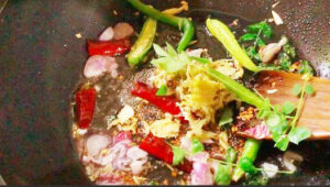 Once the mustard seed is fried (popped), add red chillies, green chillies, crushed mixture (garlic, ginger, cumin), onion and curry leaves