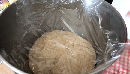 Pizza dough covered with plastic wrap