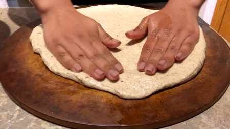 whole wheat pizza dough on pizza stone